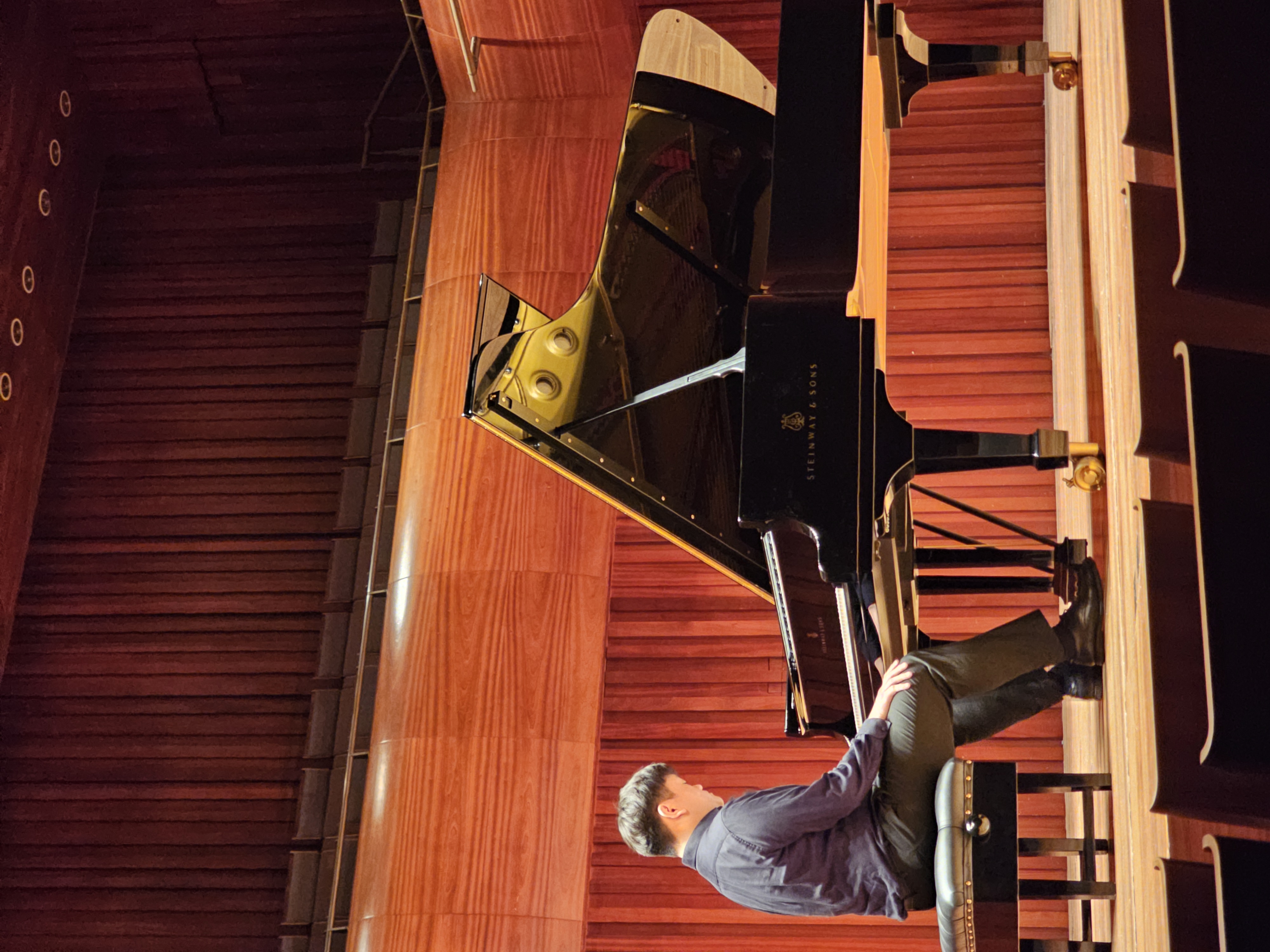 Bendit Chan seated at a grand piano in recital